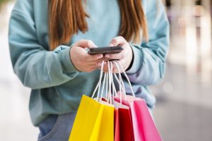 Manos sosteniendo bolsas de papel y teléfono